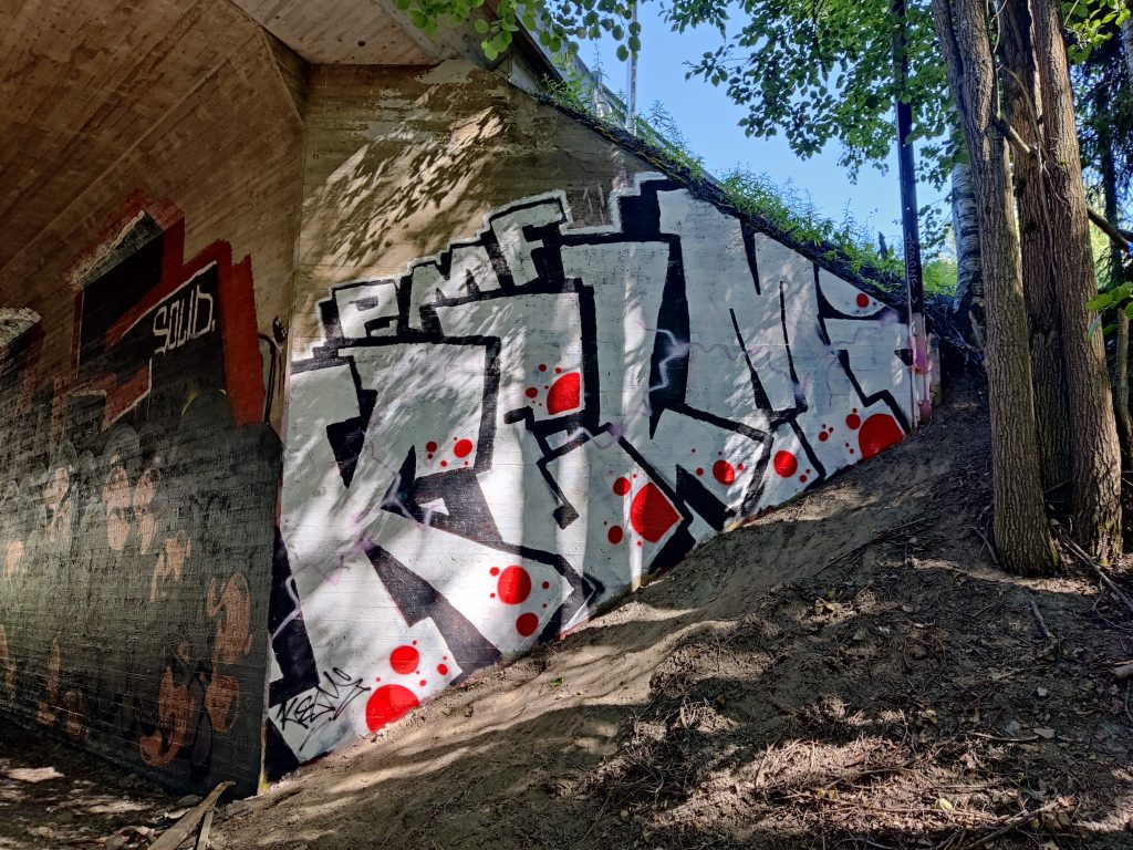 Alikulkutunnelin pääty, johon on maalattua valkomusta graffiti.